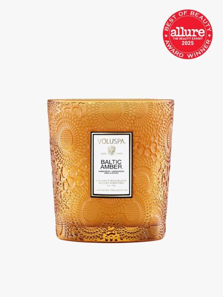 Voluspa Baltic Amber orange glass candle on light gray background with red Allure Best of Beauty seal in the top right corner